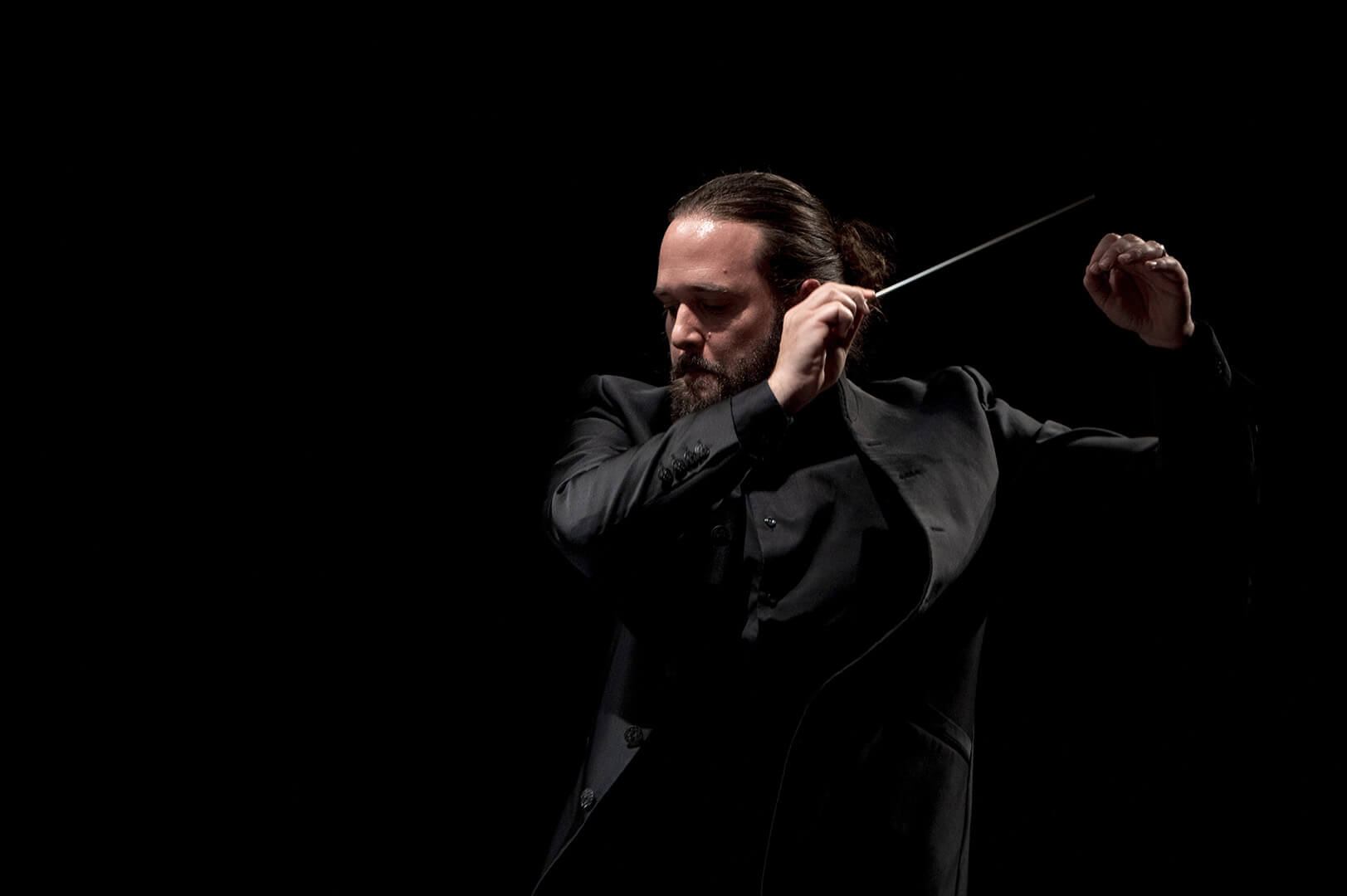 Frédéric Zosso entain de diriger un orchestre, de face, souriant.